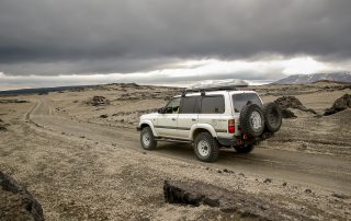 Black car on a snowy Icelandic road.