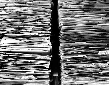 Stacked-piles-of-documents-and-files Stacked piles of documents and files in black and white, labelled with years.